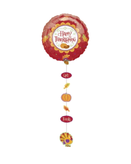 A round red foil balloon with a 'Happy Thanksgiving' design, hanging from a string with autumn-themed dangling ornaments on a plain white background.