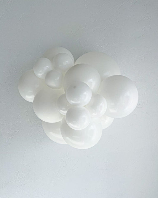 Bunch of white balloons in different sizes on a grey background.